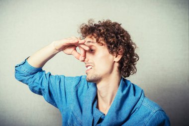 Kıvırcık saçlı adam parmaklarını kapatıyor, kötü kokuyor.