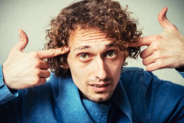 Adam işaret parmaklarını şakaklarda gösteriyor.