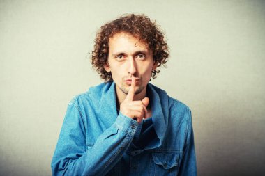 Kıvırcık saçlı adam sessiz ol diyor ve parmağını ağzına dayıyor.