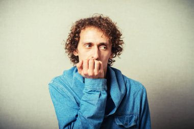 Kıvırcık saçlı adam tırnaklarını yiyor.