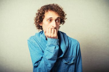 Kıvırcık saçlı adam tırnaklarını yiyor.