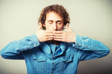 Kıvırcık saçlı adam elleriyle ağzını kapatıyor.