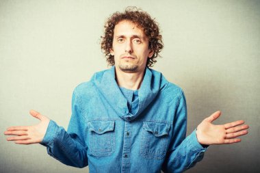 Kıvırcık saçlı adam ellerini kaldırıyor.