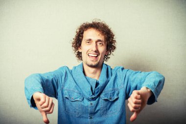 Kıvırcık saçlı adam baş parmağını kaldırıyor.