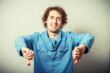 Kıvırcık saçlı adam baş parmağını kaldırıyor.