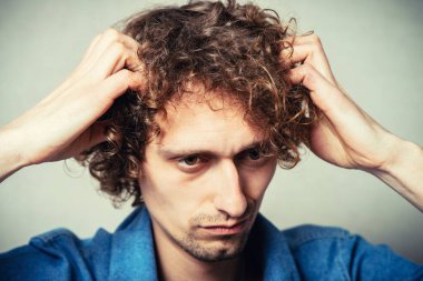 Genç adam parmağını şakağına dayayıp düşünüyor.