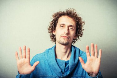 Kıvırcık genç adam jest molası. Gri bir arkaplanda