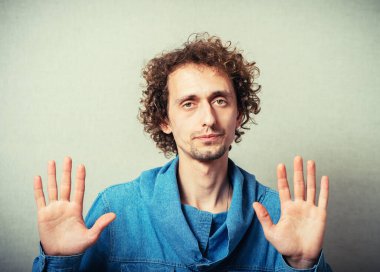 Kıvırcık genç adam jest molası. Gri bir arkaplanda