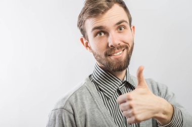 Genç adam gülümsüyor ve baş parmağını kaldırıyor..