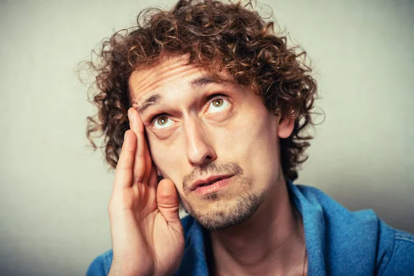 Önemli bir şey düşünen çekici bir adam. Elini şakağına dayayıp kameraya bakıyor.