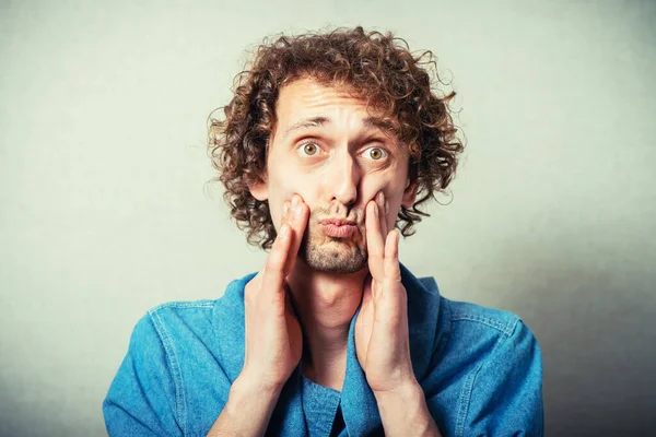 Gri arka planda diş ağrısı olan genç bir adam.