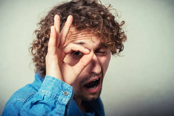 Elleri gözlerinde, parmaklarından bakan komik bir adam.