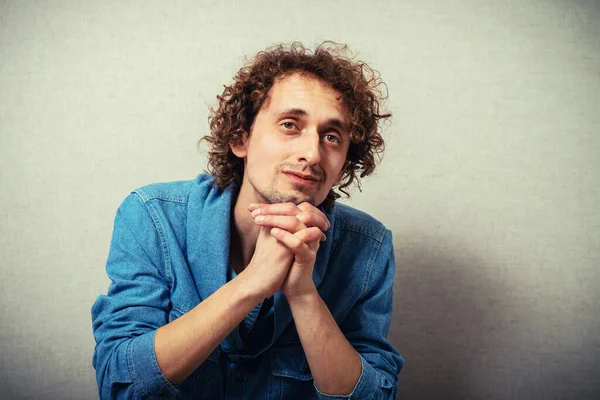 Kıvırcık saçlı adam çenesini eline dayadı.