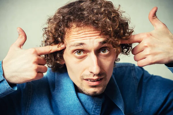 Adam işaret parmaklarını şakaklarda gösteriyor.