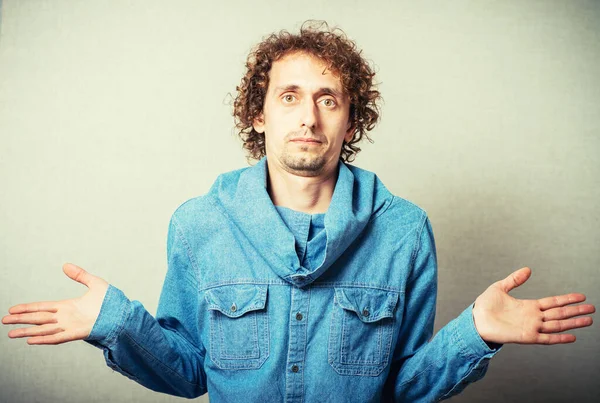 Kıvırcık saçlı adam ellerini kaldırıyor.