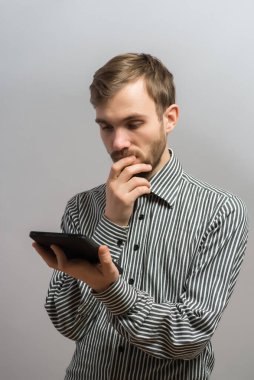 Genç adam elektronik tabletinde bir şeyler okuyor.