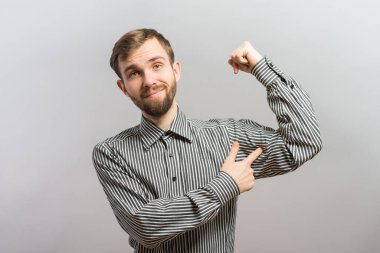 Genç adam beyaz arka planda kaslarını gösteriyor.