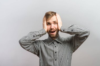 Genç adam bağırıyor ve yüzünü elinde tutuyor.