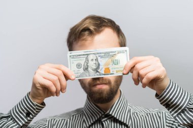 Bir dolarlık banknotla gözlerini kör eden bir iş adamı.