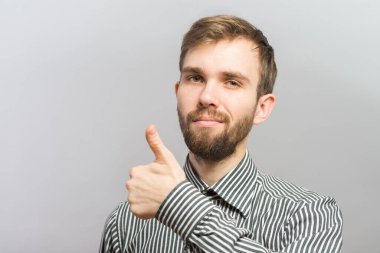Genç, sıradan bir adam baş parmağını gösteriyor ve gülümsüyor.