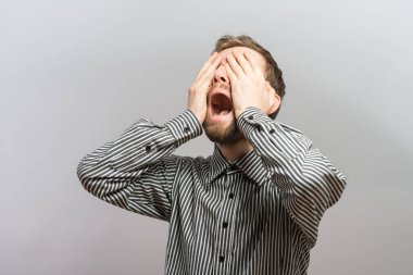 Duvarın yanında duran üzgün bir adamın portresi. Yüzünü kapatıyor.