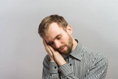 Yakışıklı genç iş adamı, elleri başının arkasında, tahta duvarda uyuyor.