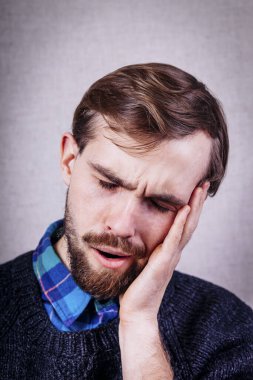 Mavi kazaklı sakallı genç adam kestiriyor.