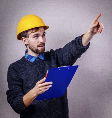 Miğferli genç inşaatçı işaret ediyor.
