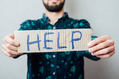 Metin içeren bir karton tutan bir iş adamı Yardım, gri arka planda izole