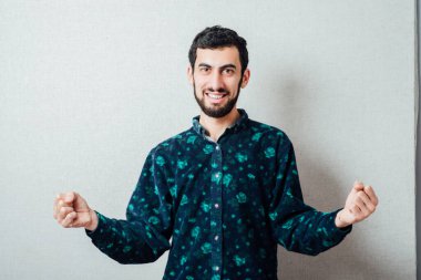 Kazanan genç adam, gri arka plana karşı bir jest yaptı 