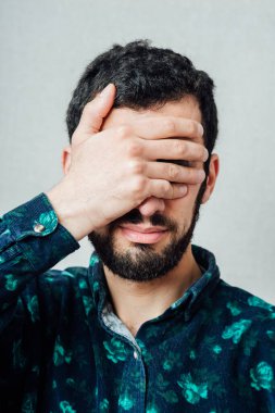 Genç ve çekici erkek elleriyle gözlerini kapatıyor.