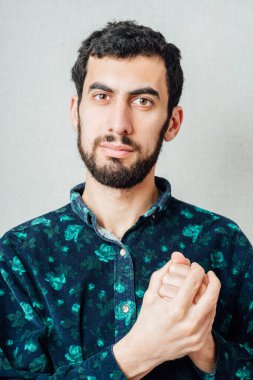 Sakallı bir adam, yumruklarını sıkıca tutuyor.