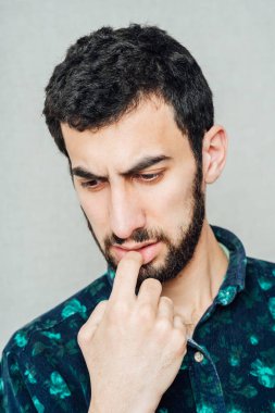 Kahverengi kazaklı sakallı genç bir adam diş ağrısı hisseder.