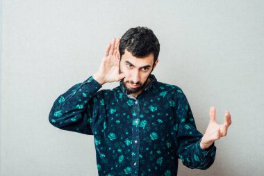 Genç, ciddi bir adam daha iyi dinlemek için kulağını tutuyor. Fotoğraf Çekimi.