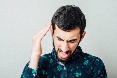 Adam, baş ağrısı ya da migrenden dolayı acı içinde ağlarken ve yüzünü buruştururken alnını ovuşturuyor.