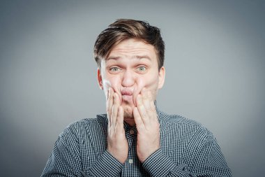 Şokta olan genç bir adam. Elleri suratında.