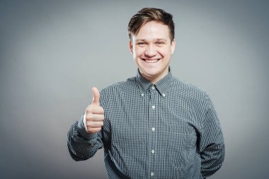 Genç adam gülümsüyor ve baş parmağını kaldırıyor.