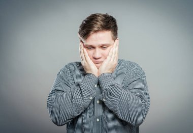 Elleri yüzü asık genç bir adam.