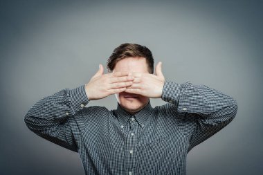 Genç adam elleriyle gözlerini kapatıyor.