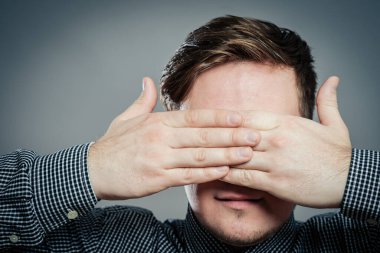 Genç adam elleriyle gözlerini kapatıyor.