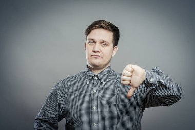 Hayal kırıklığına uğramış genç adam baş parmak işareti gösteriyor.