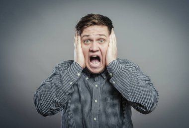 Öfkeli genç adamlar ellerini tutup çığlık atıyorlar.