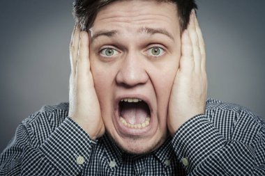 Öfkeli genç adamlar ellerini tutup çığlık atıyorlar.