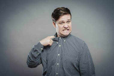 Adam gömleğinin yakasını çıkarıyor.