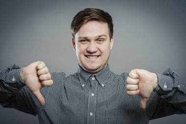 Yakışıklı genç adam başparmağını aşağı indirerek yumruğunu indirdi. Kapalı portre. Hoşnutsuz bir jest.