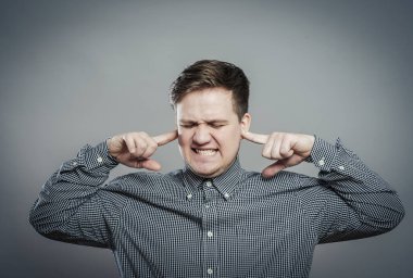 Genç adam duymak istemediği şeyleri gösteriyor. Parmakları kulaklarında