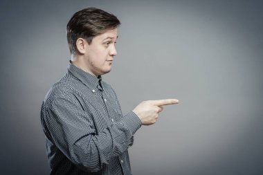 Genç adam parmağıyla birini işaret ediyor.