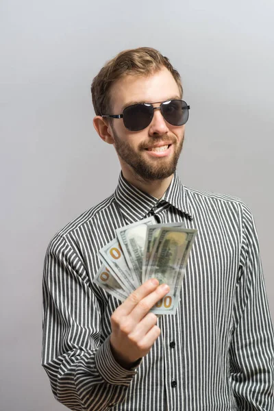 銀行券を持っている灰色の背景に隔離された若い男が — ストック写真