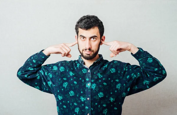 Tişörtlü, sakallı, genç bir adamın yakından çekilmiş portresi. Komşulara bakarak gürültüyü engellemek için el ele tutuşmuş.