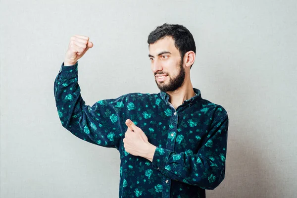 Zirveye ulaştım! Gri arka planda dururken gülümseyen mutlu genç adam.